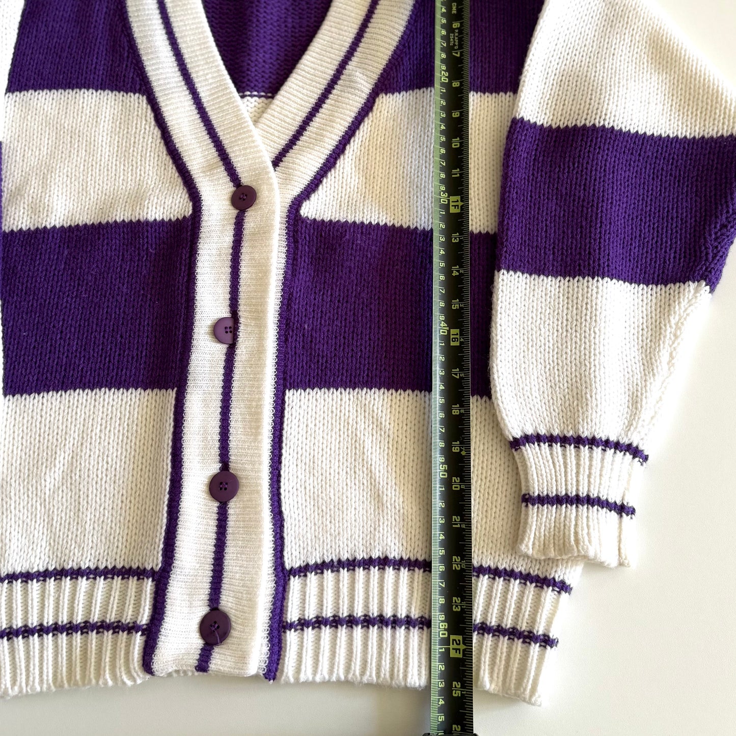 1990's preppy style - purple and white striped cardigan with a measuring tape on it on a white backdrop.