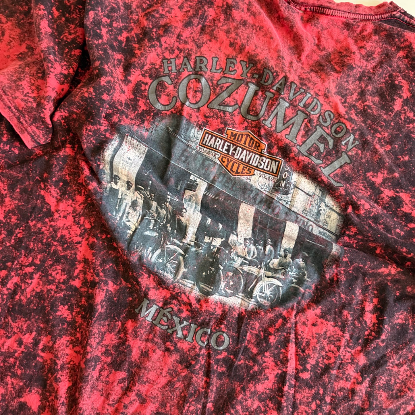 Backside close up of Pinky red t-shirt with black ie dye effect, and the harley davidson logo on the front - on a white background.
