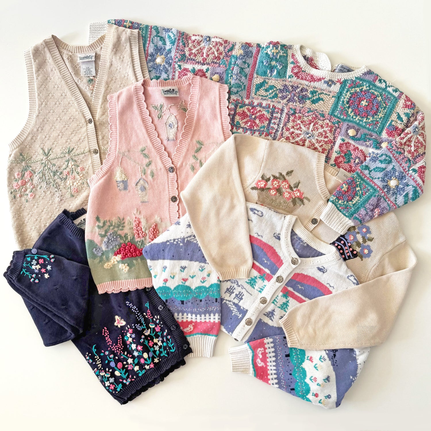 Collection of patterned sweaters and vests on a white background