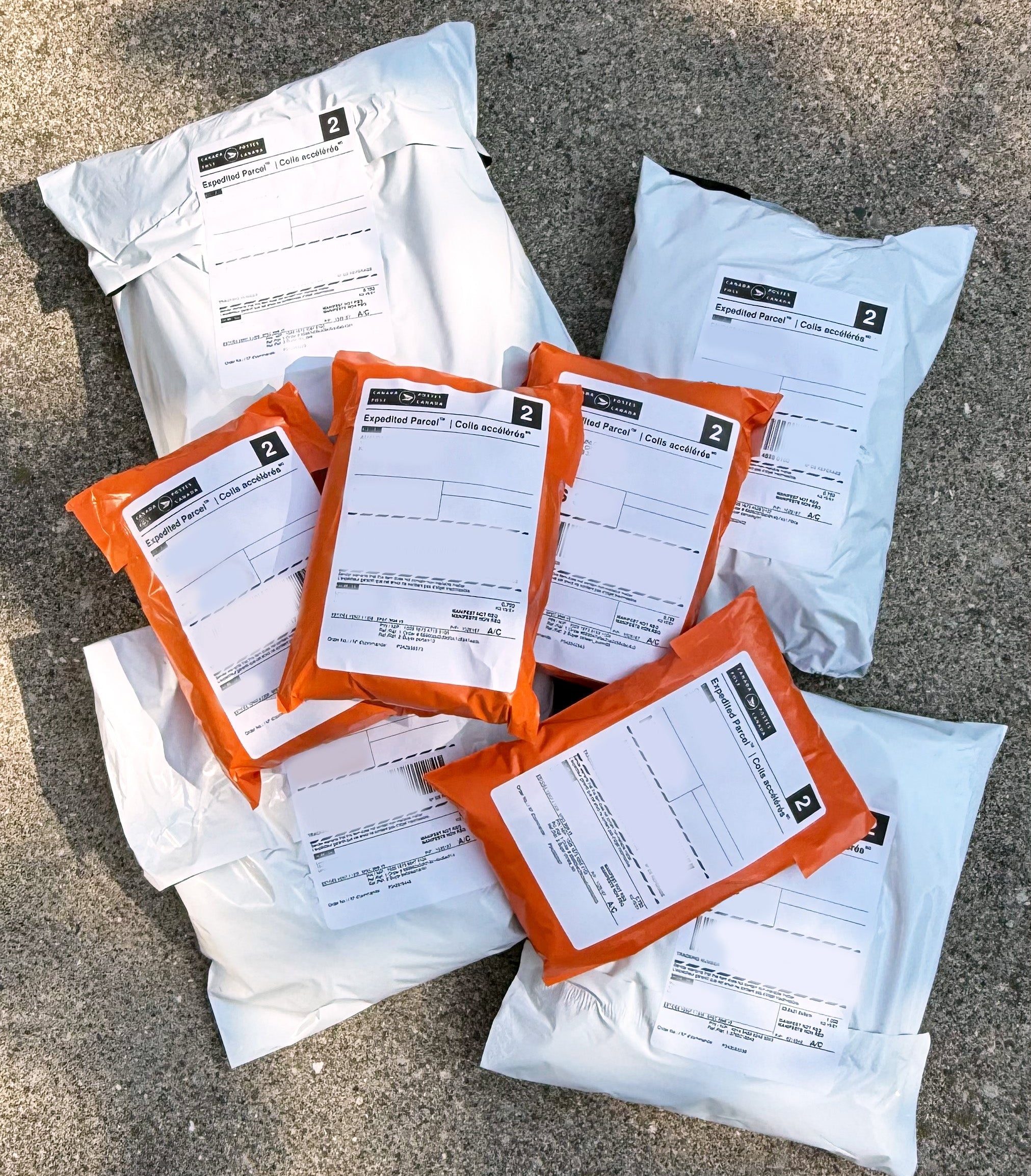 Multiple packages with orange labels on a concrete surface